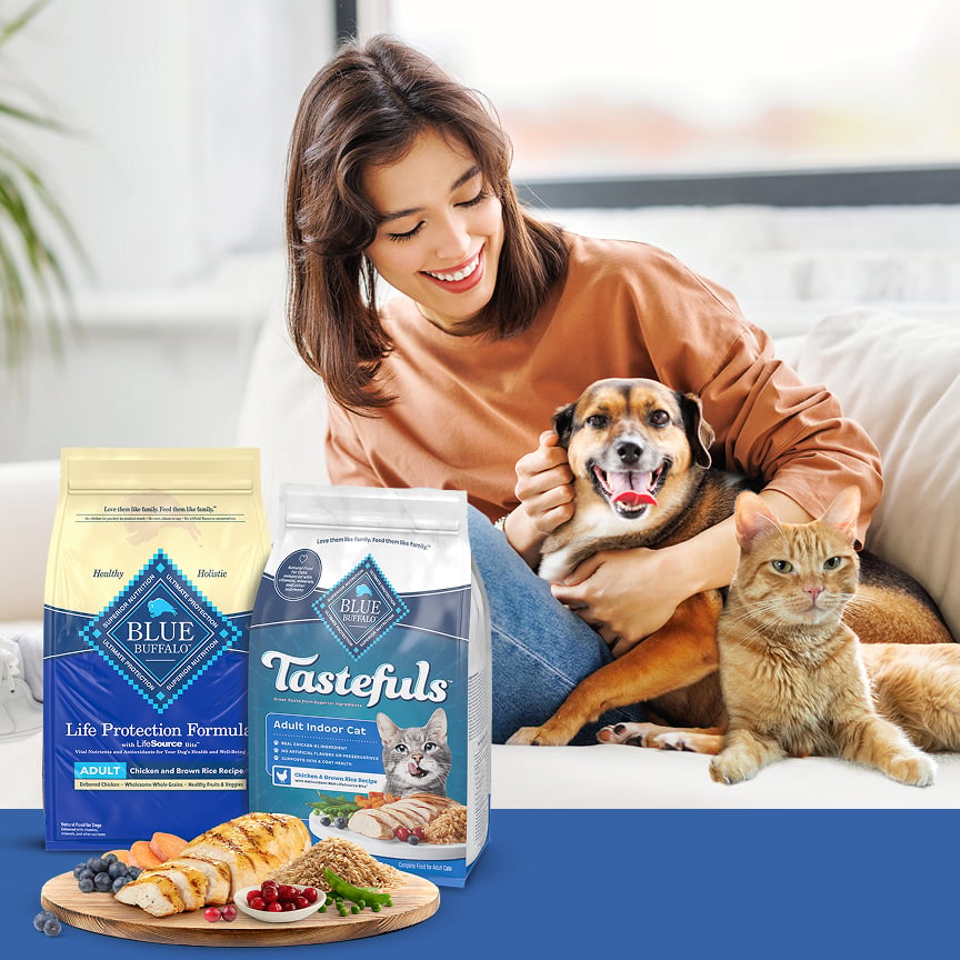 Brunette woman holding medium sized dog on couch and orange cat sitting nearby with the Best Friends Animal Society logo