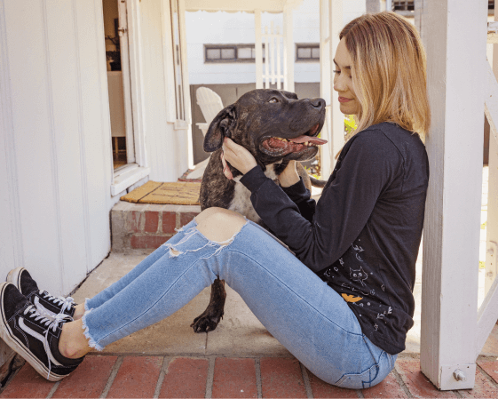 A person sitting on the porch with a dog