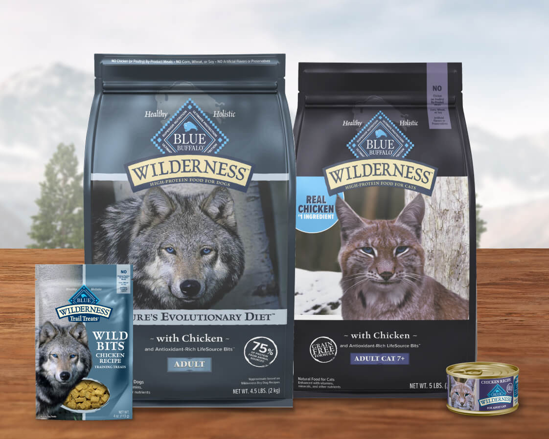 Packaging of Blue Wilderness pet food featuring a wolf, lynx, and a small can, set against a blurred nature background.