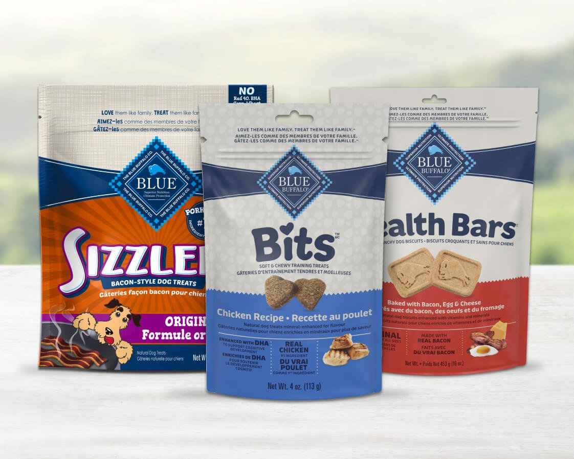 Three bags of Blue Buffalo dog treats, featuring Sizzle bacon-style treats, Bits soft-moist chicken, and Health Bars baked with bacon, egg, and cheese.