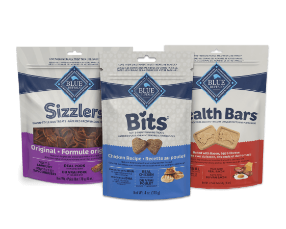 Three Blue Buffalo dog treat bags: Sizzlers Original bacon-style, Bits Chicken Recipe, and Health Bars baked with bacon, eggs and cheese
