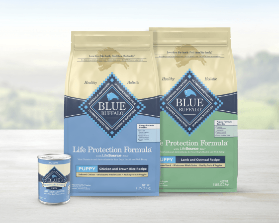 Two bags of BLUE Life Protection Formula dry puppy food and a can of BLUE Homestyle wet food for puppies.