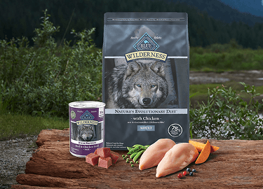 Real cuts of meat lay out on a brown wooden cutting board in a picturesque nature scene.