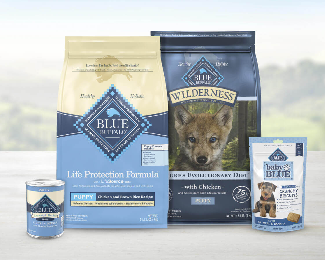 Two bags of BLUE dry dog food, a can of wet dog food, and a pack of treats for puppies.