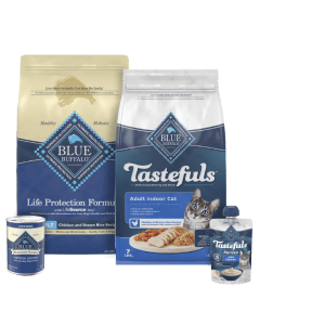 Blue Buffalo pet food products displayed, including dry kibble in bags and canned wet food, with labels indicating chicken and brown rice recipes for adult cat and dogs