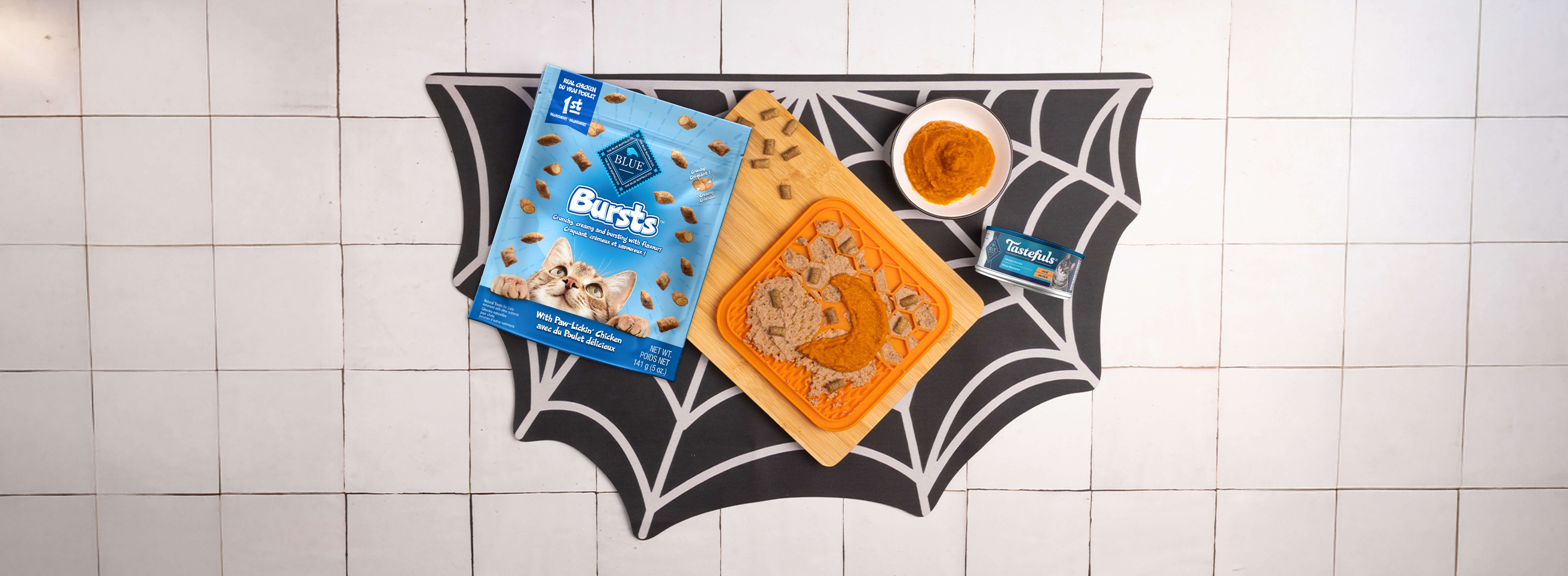 The recipe on a spider web placemat w/a lick mat, a half moon-shaped bowl, a spatula, & a bowl of Tastefuls cat food