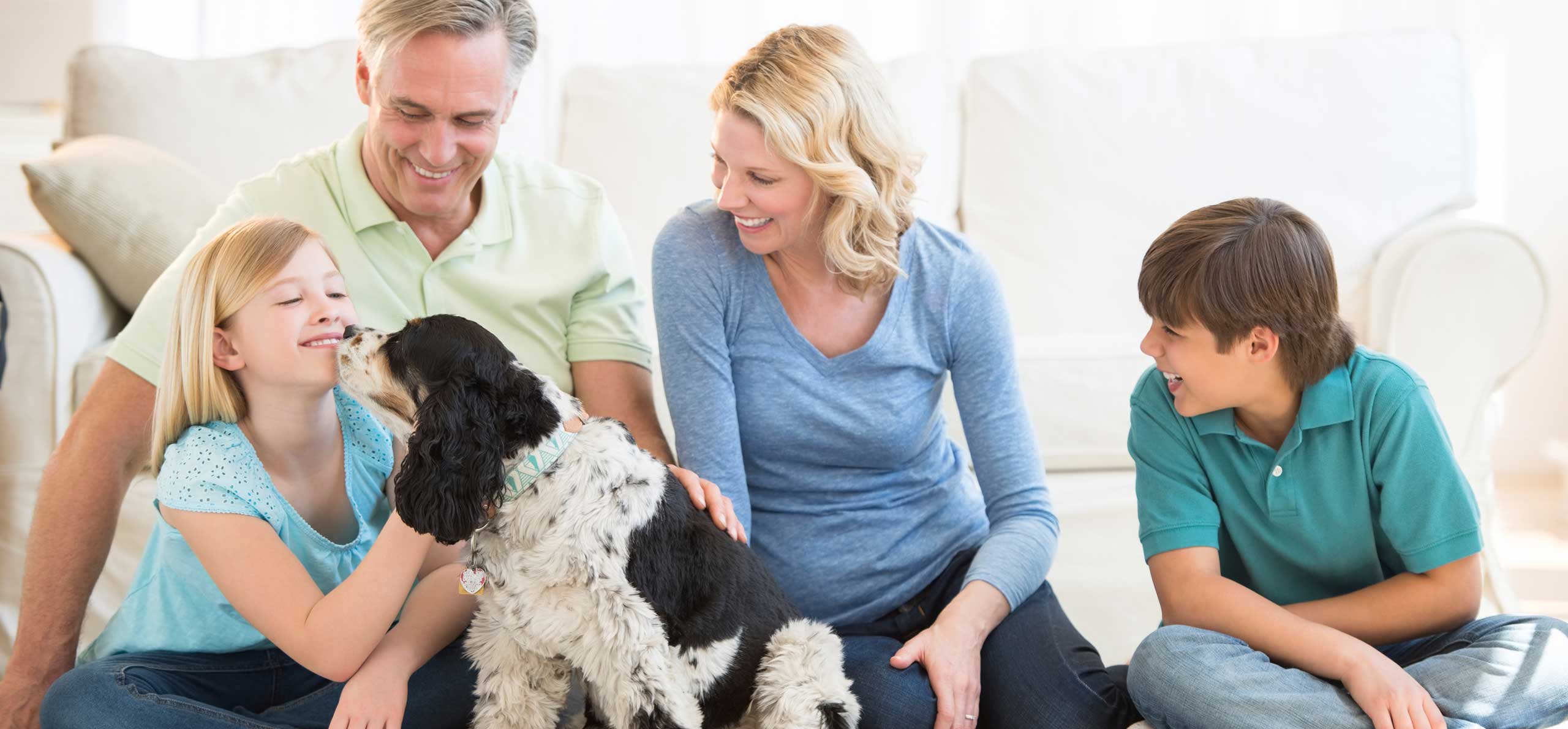 dog licking a girl with the rest of the family sitting around