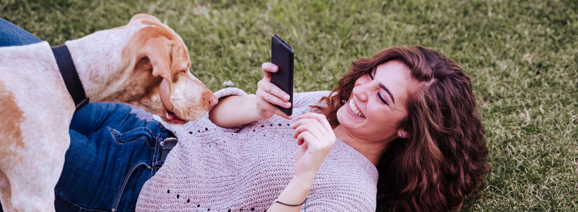 woman laying down taking photo of a dog