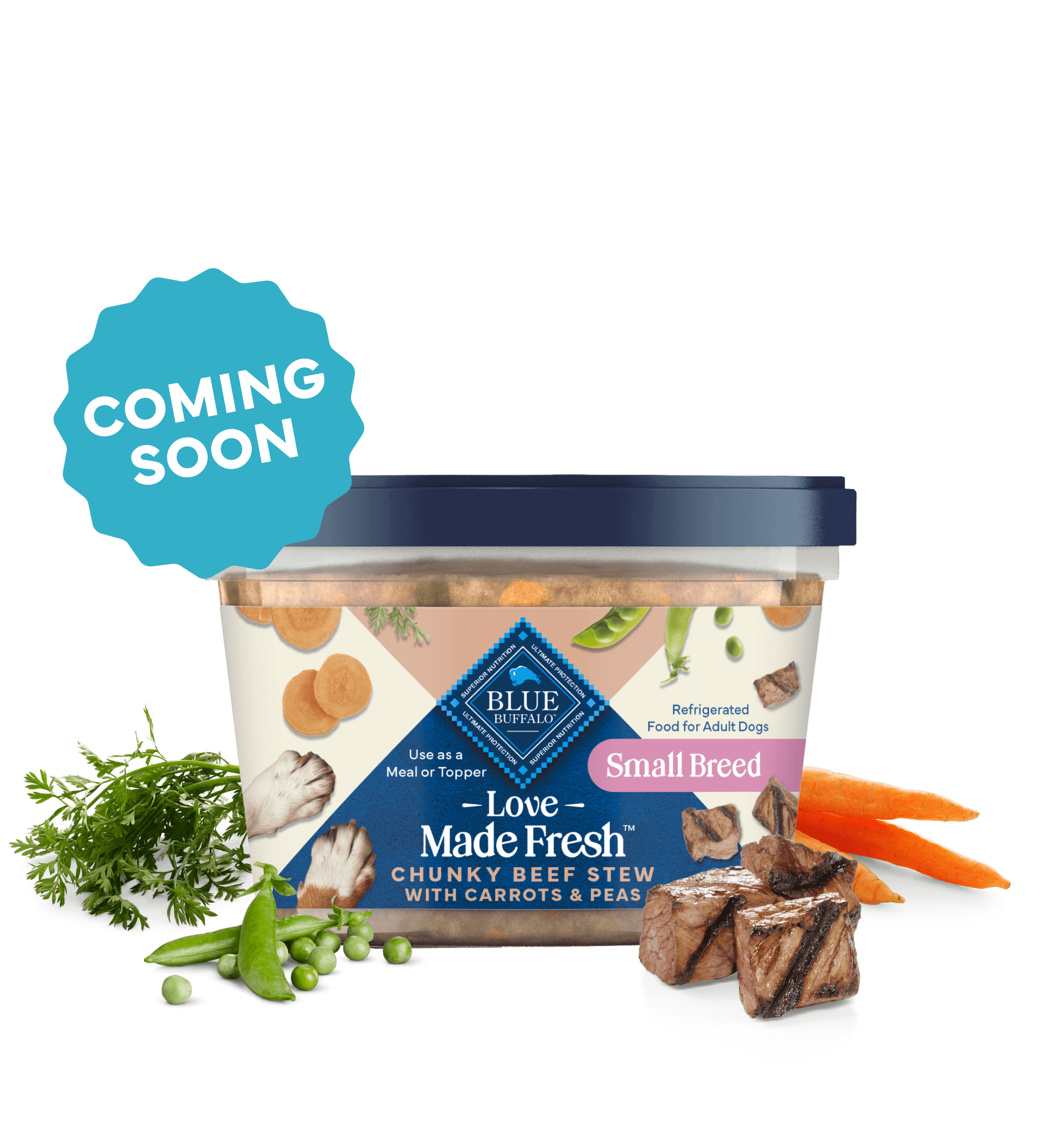 A tub of Love Made Fresh beef stew is surrounded by parsley, chunks of seared beef, carrots, and peas on a countertop.