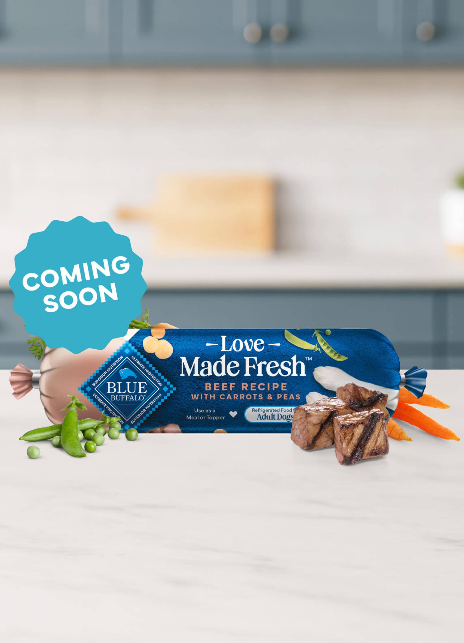 A roll of Love Made Fresh beef recipe is surrounded by parsley, chunks of seared beef, carrots, and peas on a countertop.