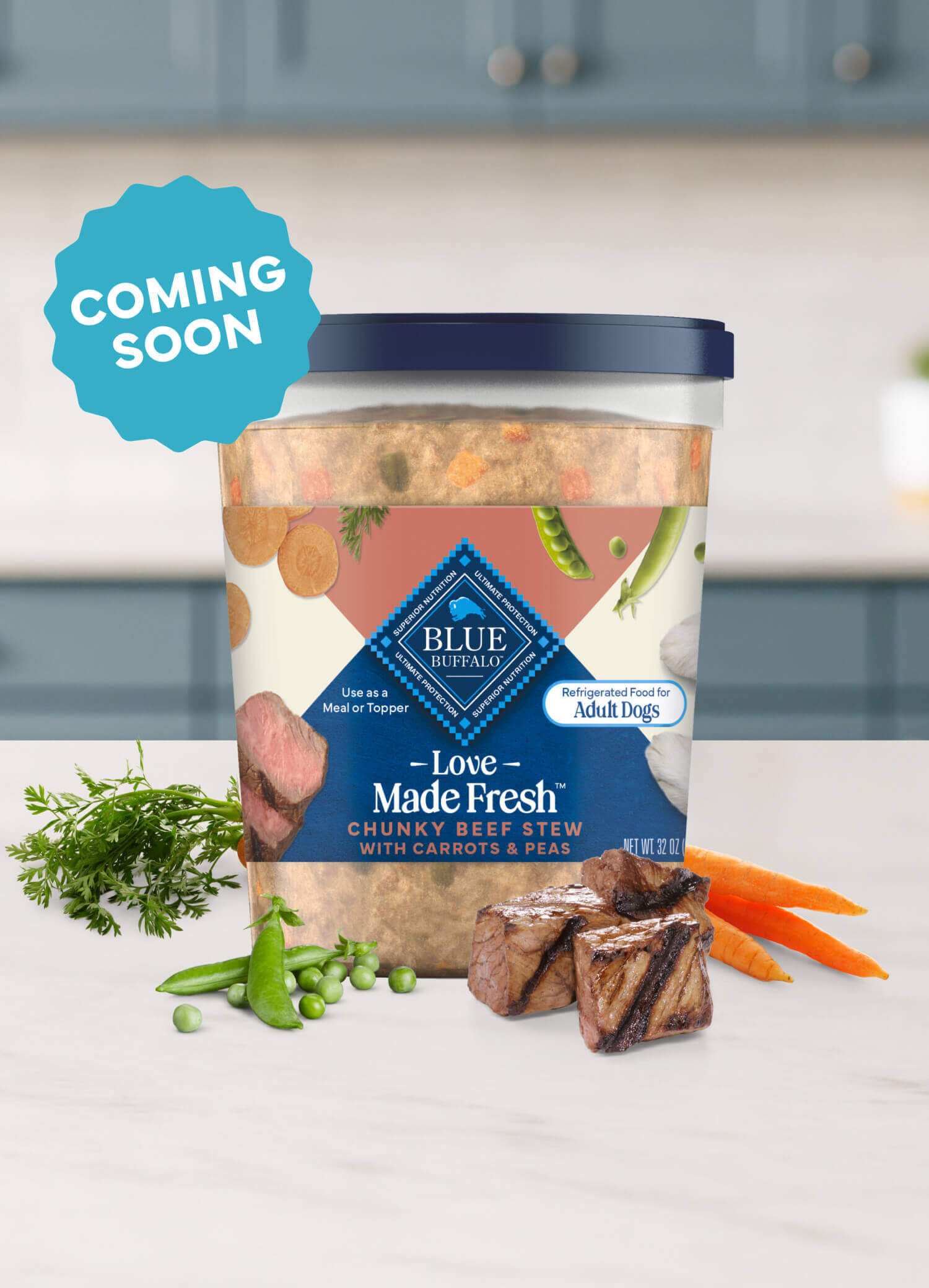 A tub of Love Made Fresh beef stew is surrounded by parsley, chunks of seared beef, carrots, and peas on a countertop.