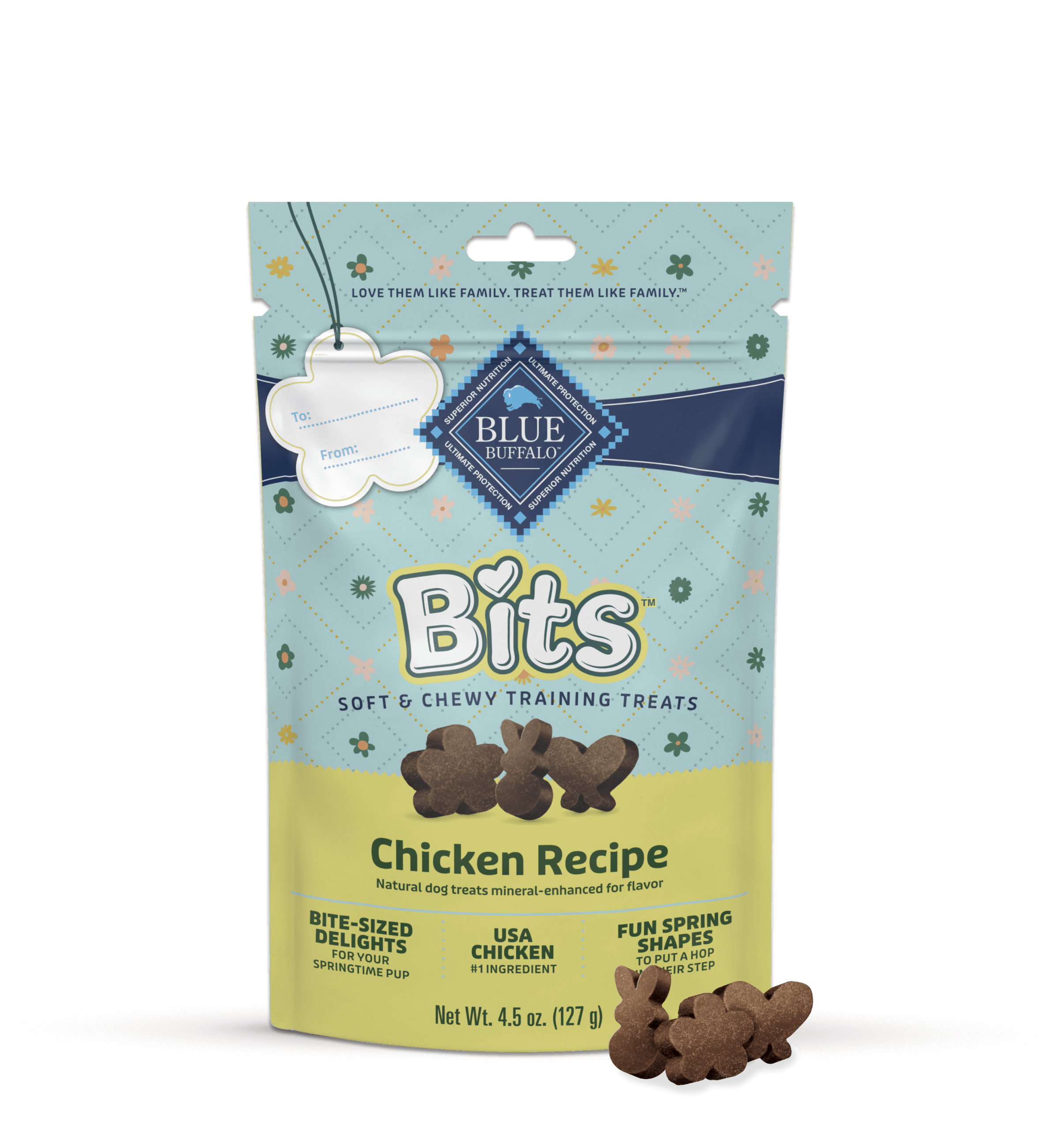 A pack of BLUE Bits chicken recipe dog treats is sitting on a counter in front of bright green grass.