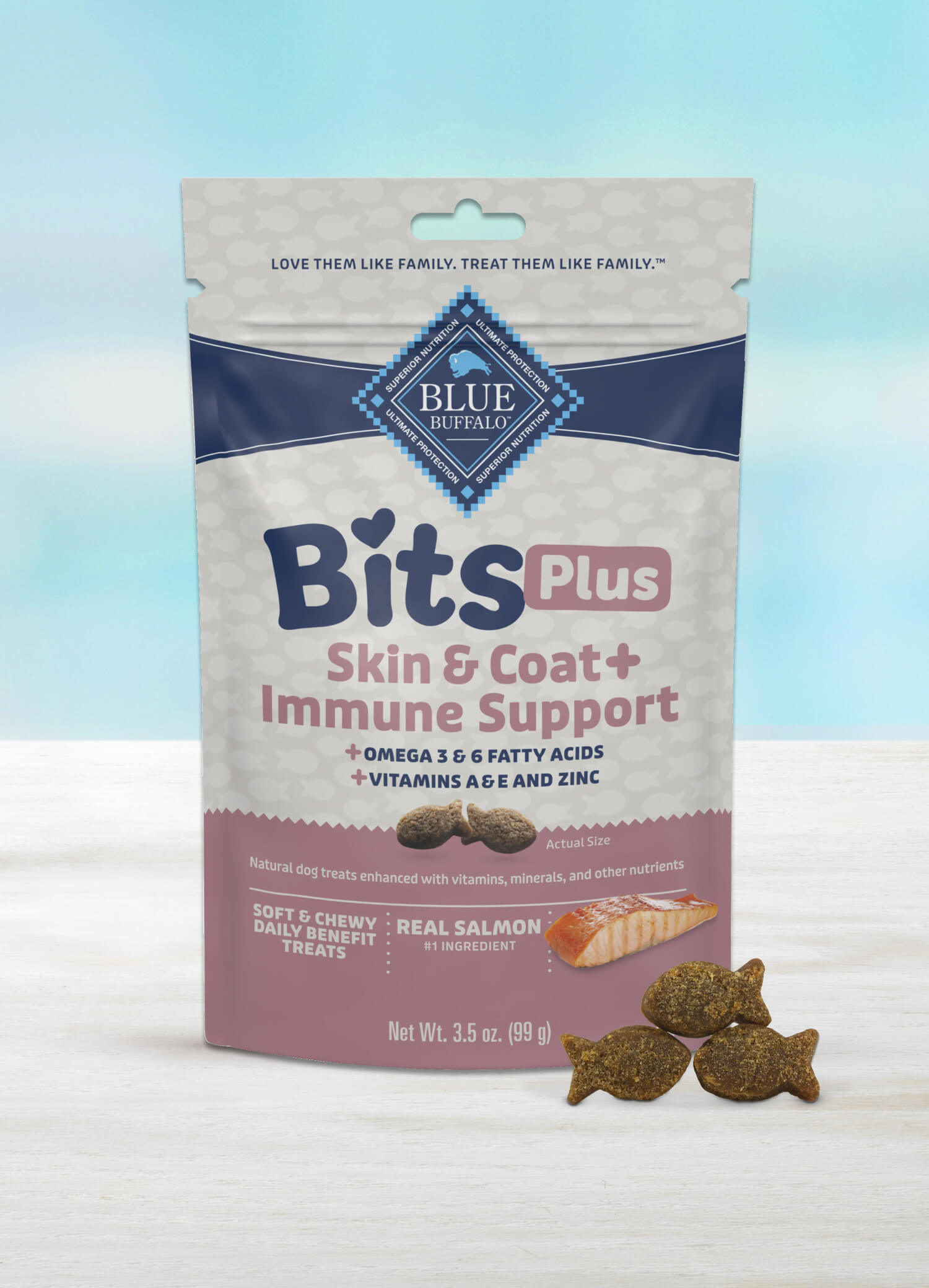 A package of BLUE Bits Plus Skin & Coat + Immune Support soft and chewy dog training treats with a few fish-shaped treats neatly stacked in front.