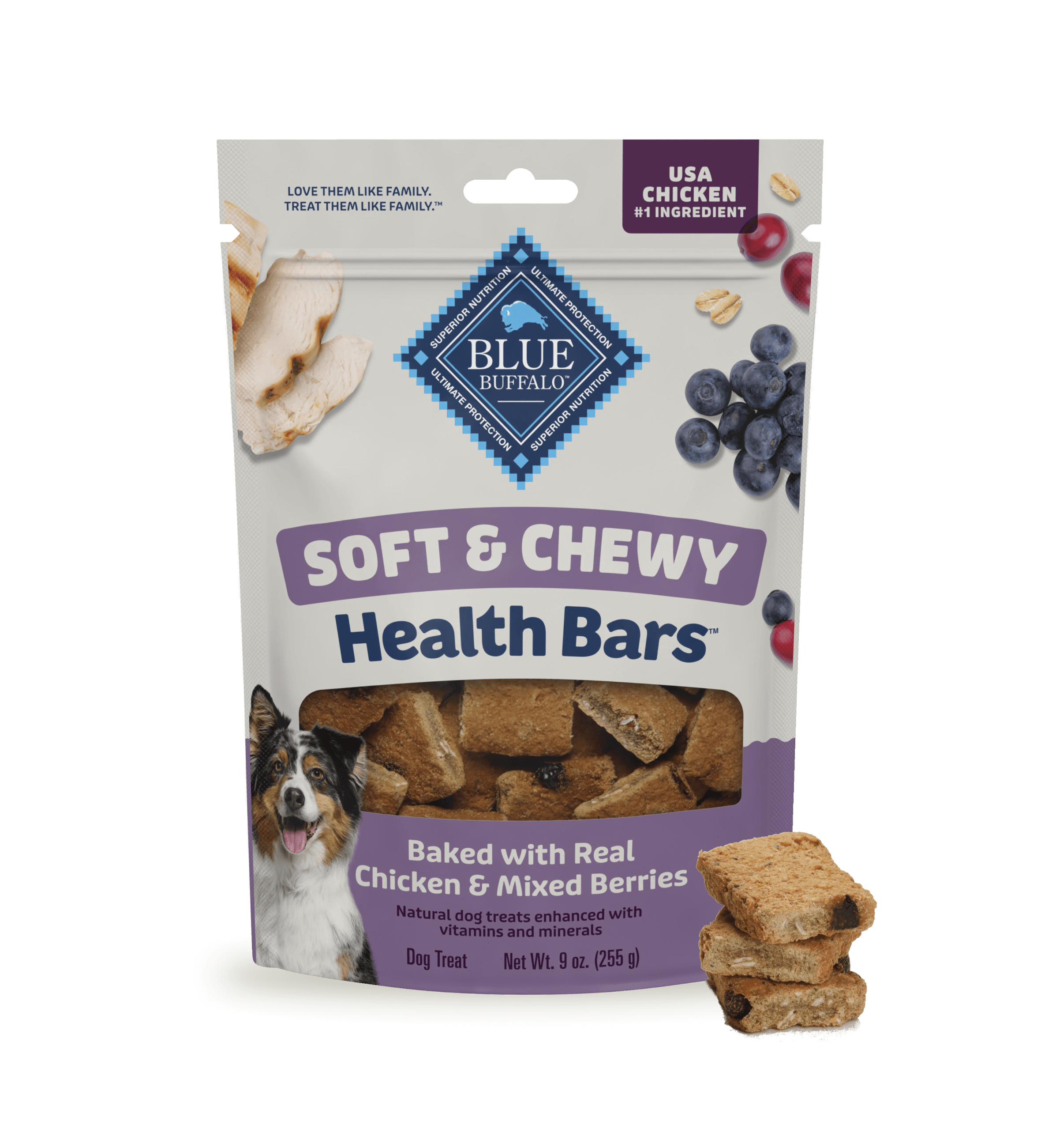 A bag of BLUE dog treats sits on a light surface against a blue-and-white background. The package shows juicy berries, pieces of tender chicken, and a happy dog. A small stack of treats sits beside the treat bag.