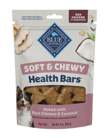  A package of BLUE dog treats shows fresh coconut, pieces of tender, juicy chicken, and a happy dog. A small stack of treats sits beside the treat bag.